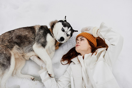 冬天遛狗摄影照片_开朗的女人冬装在雪地里遛狗新鲜空气