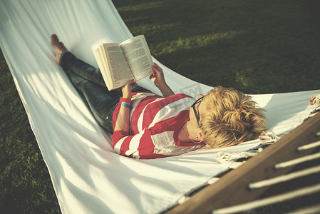 女人在吊床上放松时看书