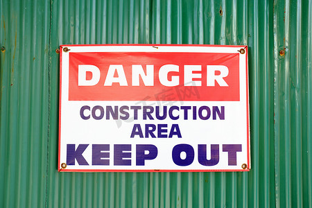 请勿图标摄影照片_绿色锌墙背景上的“危险建筑区域请勿入内”标志。