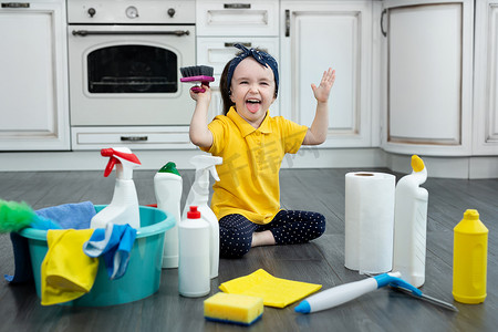 小女孩在清洁时在厨房地板上玩洗涤剂和刷子