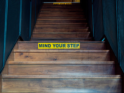 小心你的脚步，木台阶上黄色警告标志上的黑色文字