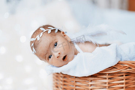 花天使摄影照片_可爱的新生婴儿天使从婴儿篮里望去。
