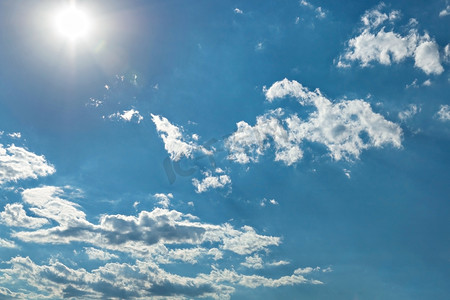 白色云朵背景摄影照片_明亮的阳光，白色的云朵和蓝天上明亮的阳光。
