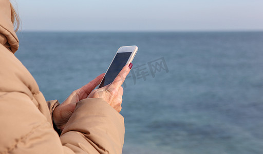 美丽的女人在海滩上使用智能手机