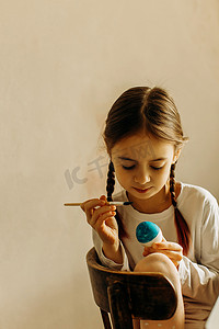 可爱的小女孩画着蓝色和黄色的复活节彩蛋。