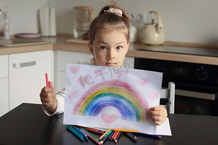 女孩在家里画彩虹，这是英国国家医疗服务体系 (NHS) 的象征。