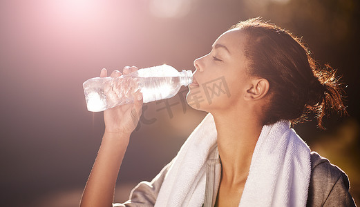 多喝水....拍摄一位年轻女子在锻炼后喝一瓶水。