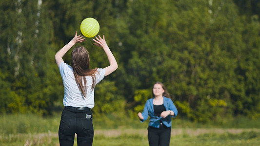 两个女朋友在草地上打排球。