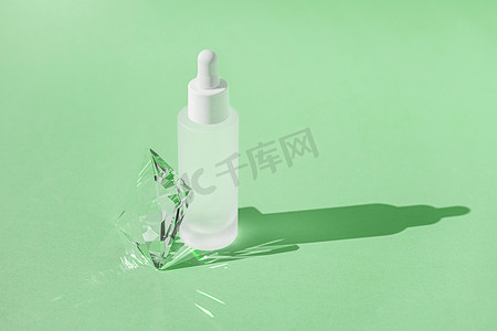 玻璃窗厚度摄影照片_白瓶中含有胶原蛋白和肽的血清护肤产品，绿色背景上带有滴管，带有水晶玻璃棱镜折射光效和光线。