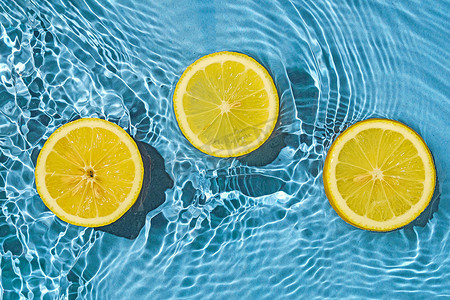 柠檬柑橘热带异国水果在蓝色透明淡水中与运动波。