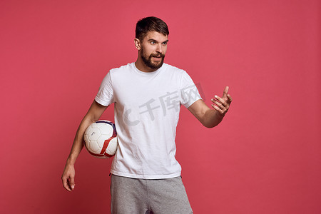 指手画脚的人摄影照片_在粉红色背景能量上拿着足球的男人用他的手教练情绪模型指手画脚