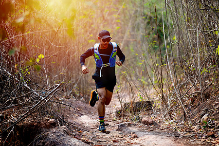 一名男子越野跑者和运动员脚穿着运动鞋在森林里越野跑