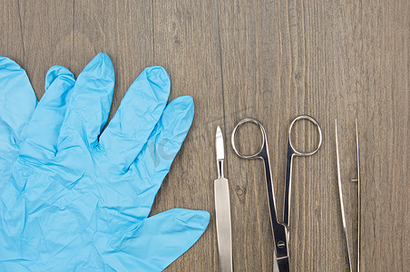 蓝色乳胶手套旁边的特写银手术刀手术剪刀和镊子