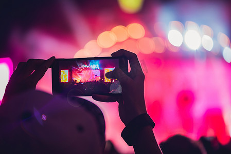 人们在音乐节上享受摇滚音乐会并用手机拍照