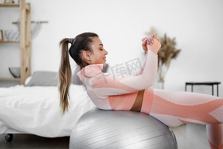 腹肌锻炼摄影照片_在家里用健身球做腹肌锻炼的运动型女性