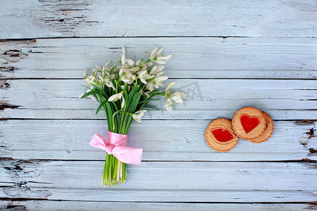花上的雪摄影照片_木制背景上带粉红丝带和饼干的雪花莲
