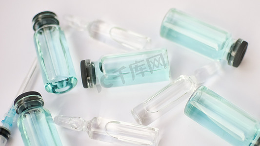 小瓶疫苗，白色背景上透明和蓝色液体的玻璃安瓿顶视图，全球疫苗接种概念