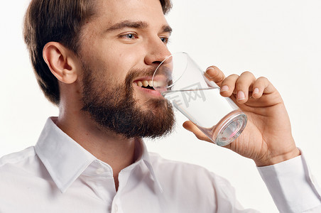 快乐的男人从浅色背景的白衬衫肖像模型上的玻璃杯里喝水