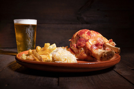 大鹅炖酸菜摄影照片_传统的德国美食烤火腿、酸菜和啤酒，啤酒节背景。