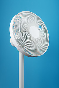 白色科技风背景摄影照片_一种设计现代的高科技白色电风扇，用于在蓝色背景下为房间降温