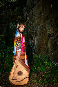 身着民族服饰、带着班杜拉乐器的乌克兰妇女站在一块岩石旁