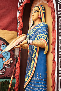 印度西孟加拉邦库拉，2018年5月 — 在西孟加拉邦一个印度乡村的泥屋里，一位部落老妇人的雕像站在庭院里，手里拿着竹子“Kulo”。