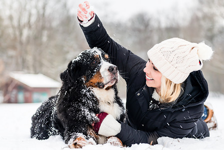 冬天遛狗摄影照片_女人在雪地里抱着她的狗