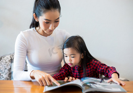 一位亚洲母亲正在教她的女儿读书