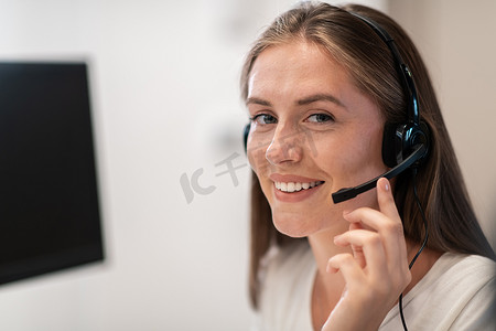 icon热线摄影照片_呼叫中心戴着耳机的热线女接线员。戴着耳机在呼叫中心工作的女商人。