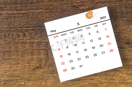 2022 年 5 月日历和木制背景上的木制图钉。