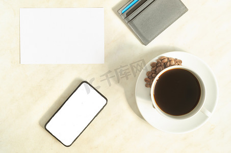 一杯加咖啡豆的咖啡、带模型的手机、银行卡和桌上的空白。