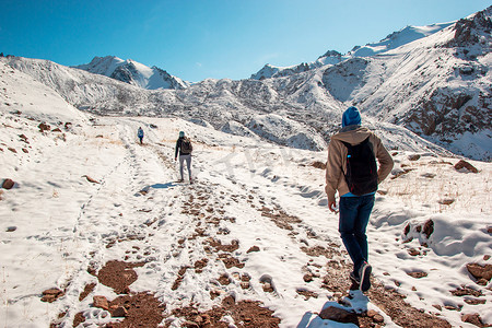 雪顶摄影照片_山路上的三名游客爬上雪顶。