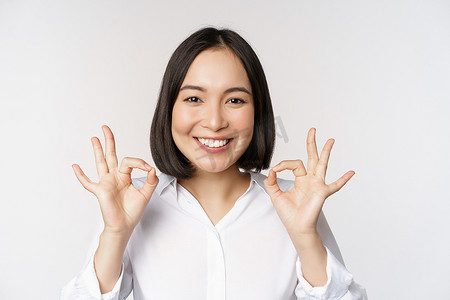 特写亚洲女孩头像，显示好，好标志，满意微笑，推荐，高兴，赞美和恭维，白色背景