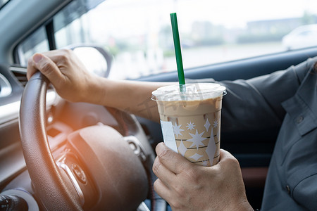 咖啡车摄影照片_亚洲女士在车里拿着冰咖啡很危险，有发生事故的风险。
