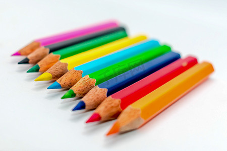 多色束各种彩虹色铅笔排成一排，并排排列在白色背景中，平躺。