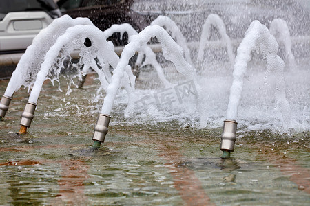 水柱摄影照片_泡沫浓密的水柱在运动中冻结，从城市喷泉的金属喷嘴中喷出。