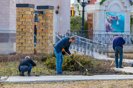 园林工具摄影照片_工人在城市公园内进行景观美化，用园林工具清理花坛。