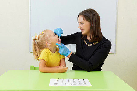 言语治疗师在办公室训练发音时与小女孩一起工作