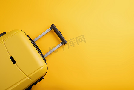 纯黄色背景复制空间上的顶视图黄色旅行包或手提箱。