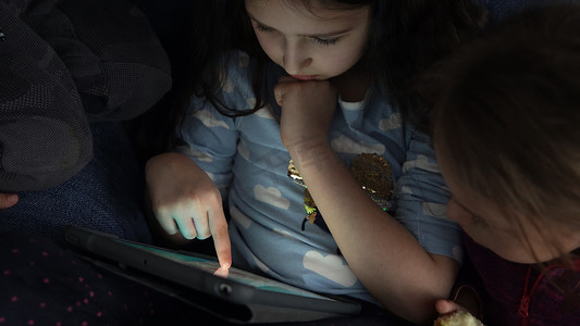小手卡通摄影照片_正宗的 3 个学龄前幼儿未成年儿童孩子兄弟姐妹一起在家里的智能手机设备笔记本电脑平板电脑上观看卡通玩游戏在线聊天。