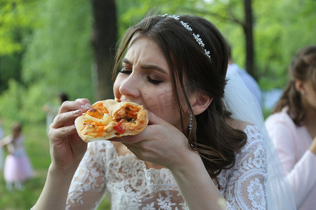 婚礼照片新娘在户外在森林里吃披萨