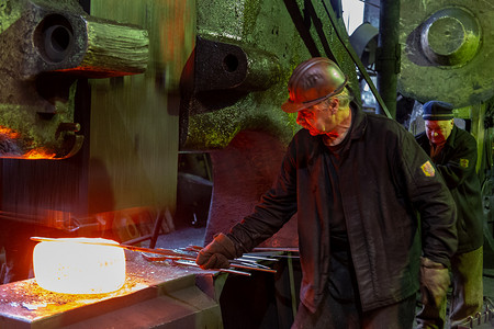 铁匠工人在老工厂锻造大块热钢