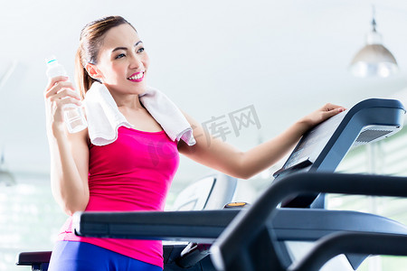微笑的女人在跑步机上展示水瓶
