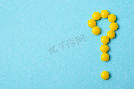 黄色药丸作为蓝色背景上的问号，带有复制空间