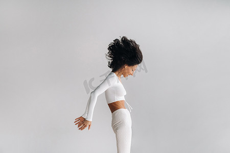 健身房运动卡摄影照片_一位身穿白色运动服的女士正在瑜伽馆进行动态卡利冥想