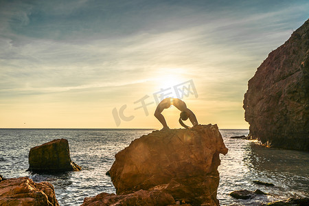 海边女子摄影照片_女子体操运动员正在海边夕阳的沙滩上训练。
