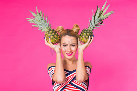 粉色菠萝摄影照片_粉红色背景中带菠萝的时尚肖像滑稽女人