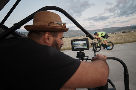 摄影师在骑自行车时拍摄铁人三项运动员的动作镜头