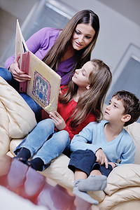 孩子和母亲摄影照片_年轻的妈妈在家里和孩子们一起玩，看书