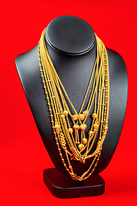 项链展示架，红色天鹅绒面料上有金项链。